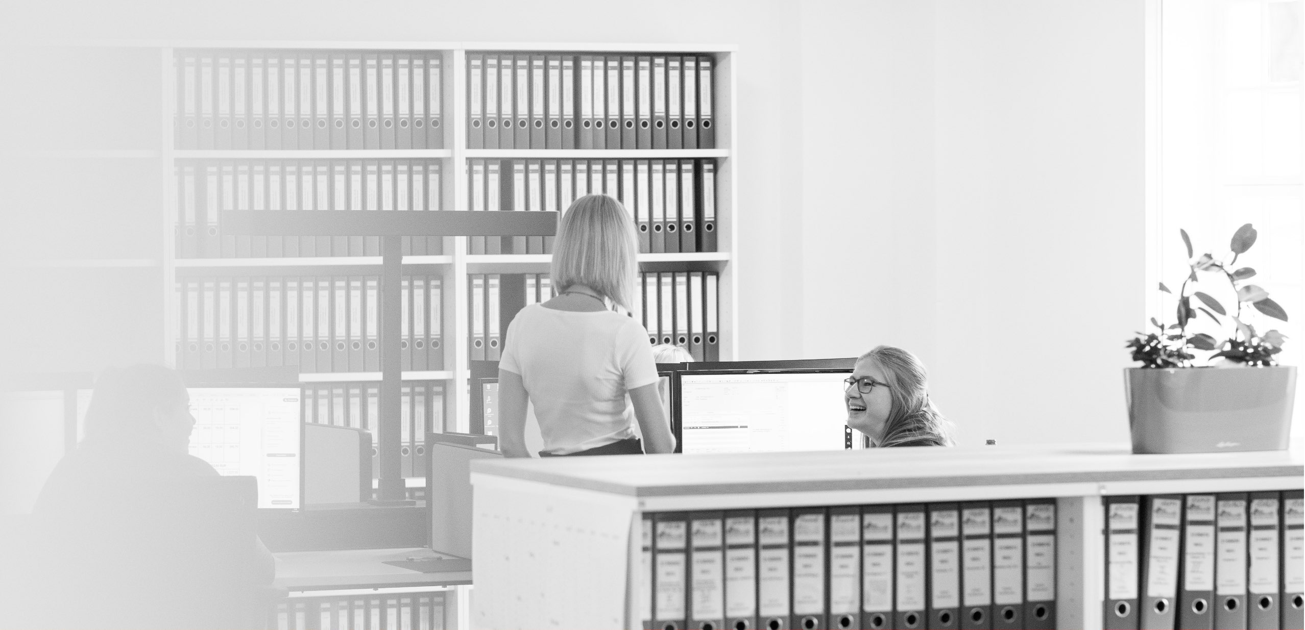 Schwarzweißaufnahme: Blick in ein Büro der Honora mit Mitarbeiterinnen bei der Arbeit