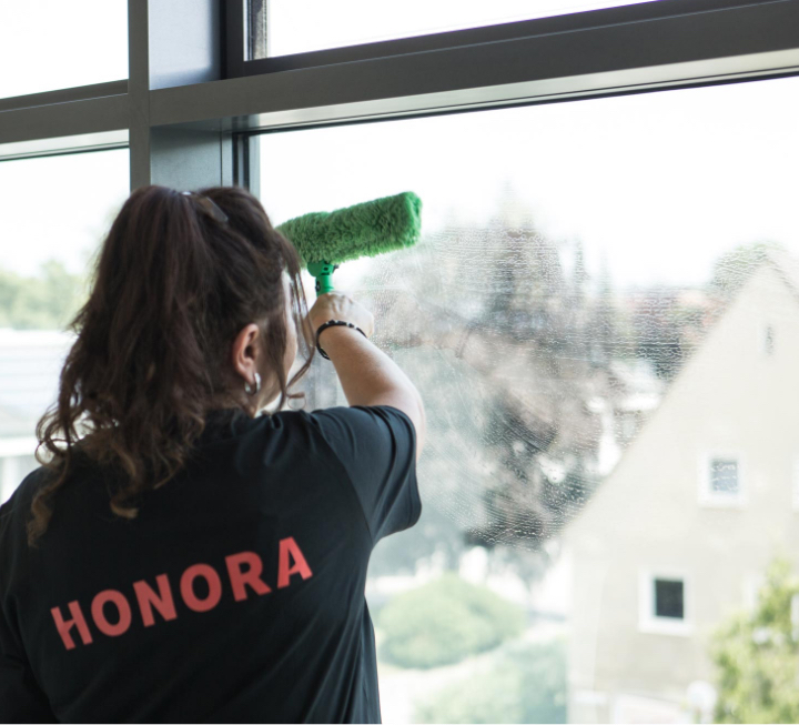 Reinigungsservice: Eine Mitarbeiterin des Hausmeisterservice putzt die Fenster in einer Immobilie in Augsburg