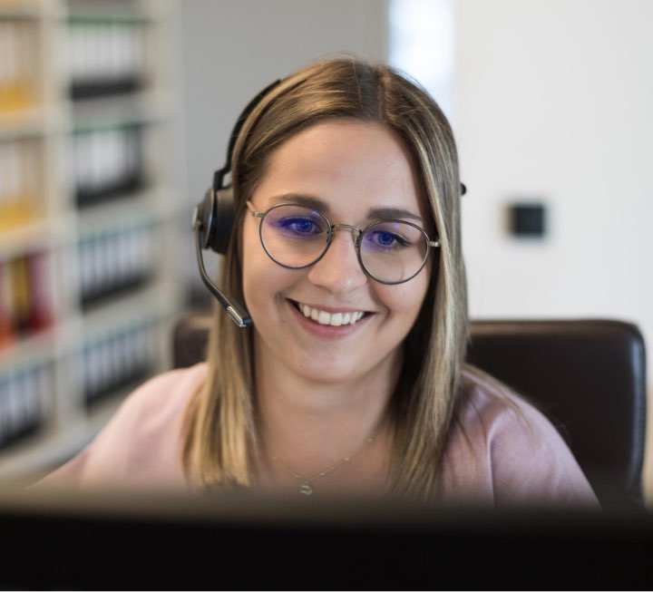 Eine Mitarbeiterin der Hausverwaltung kümmert sich am Telefon mit Headset um die Wünsche eines Kunden